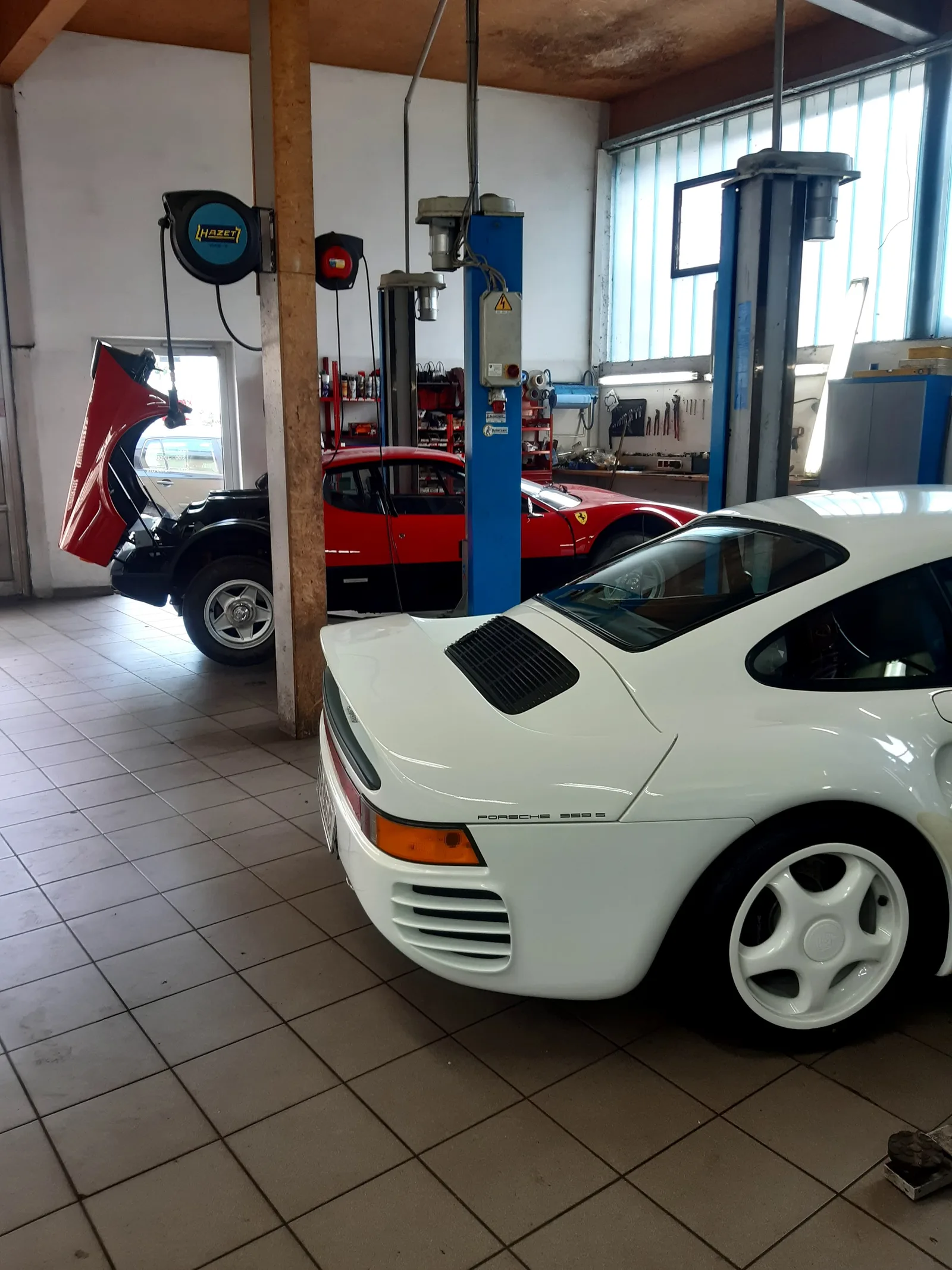 Werkstatthalle mit mehreren Sportwagen und Hebebühnen